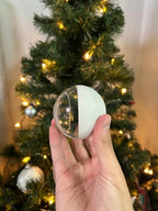 Nostalgie Orb v dlani před rozsvíceným vánočním stromkem